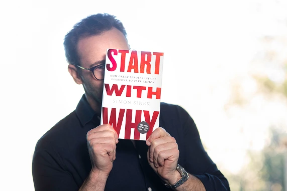 Simon Sinek holding Start With Why book